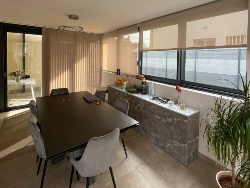 Stores intérieurs beige, baies alu noir, table marbre et chaises velours gris