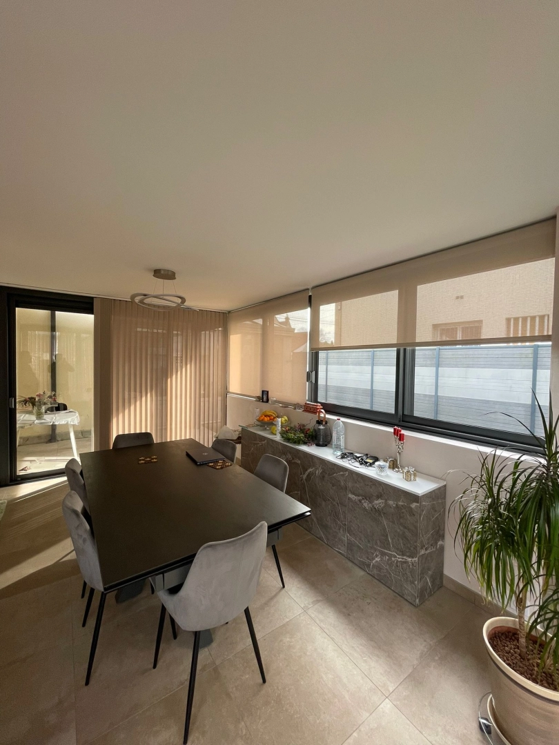Stores intérieurs beige, baies alu noir, table marbre et chaises velours gris
