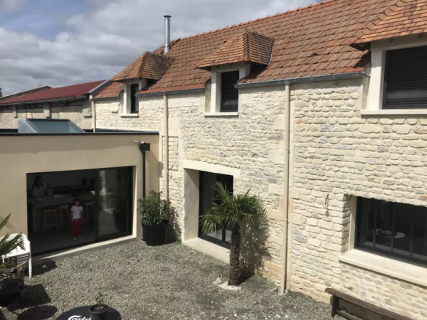 Longère en pierre rénovée, extension toit plat crème, menuiseries alu noires et baie coulissante
