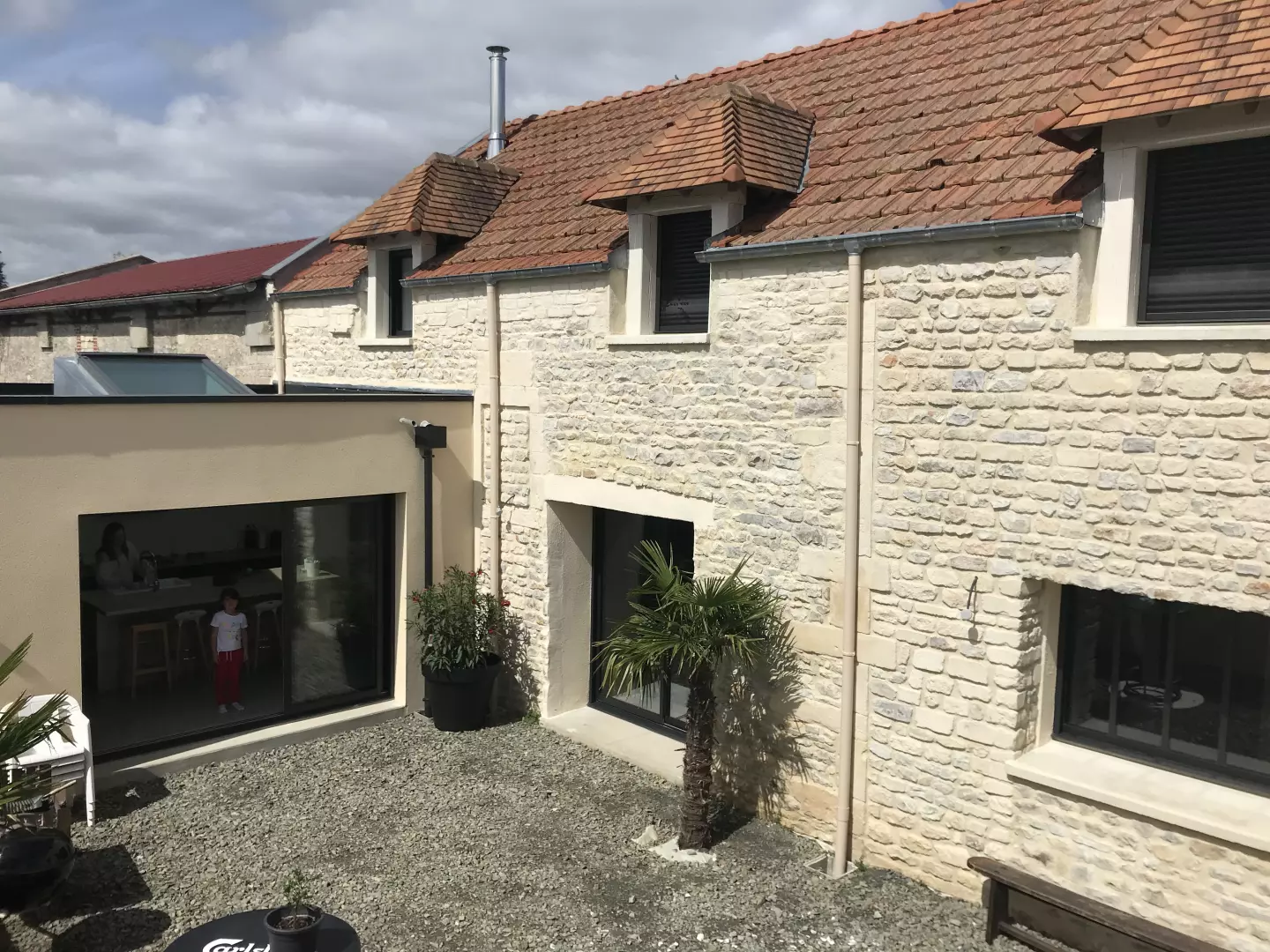 Longère en pierre rénovée, extension toit plat crème, menuiseries alu noires et baie coulissante