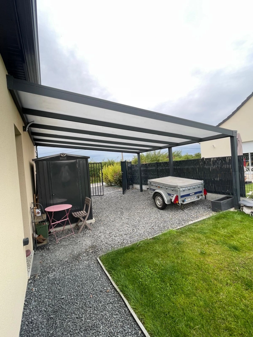 Carport alu anthracite adossé, toiture blanche, gravier, abri de jardin et remorque