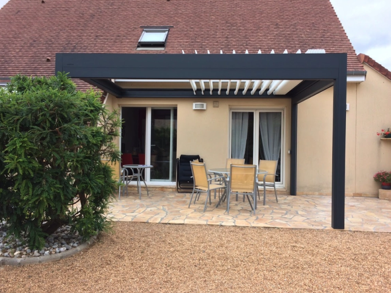 Pergola bioclimatique anthracite, lames blanches, terrasse pierre naturelle et salon