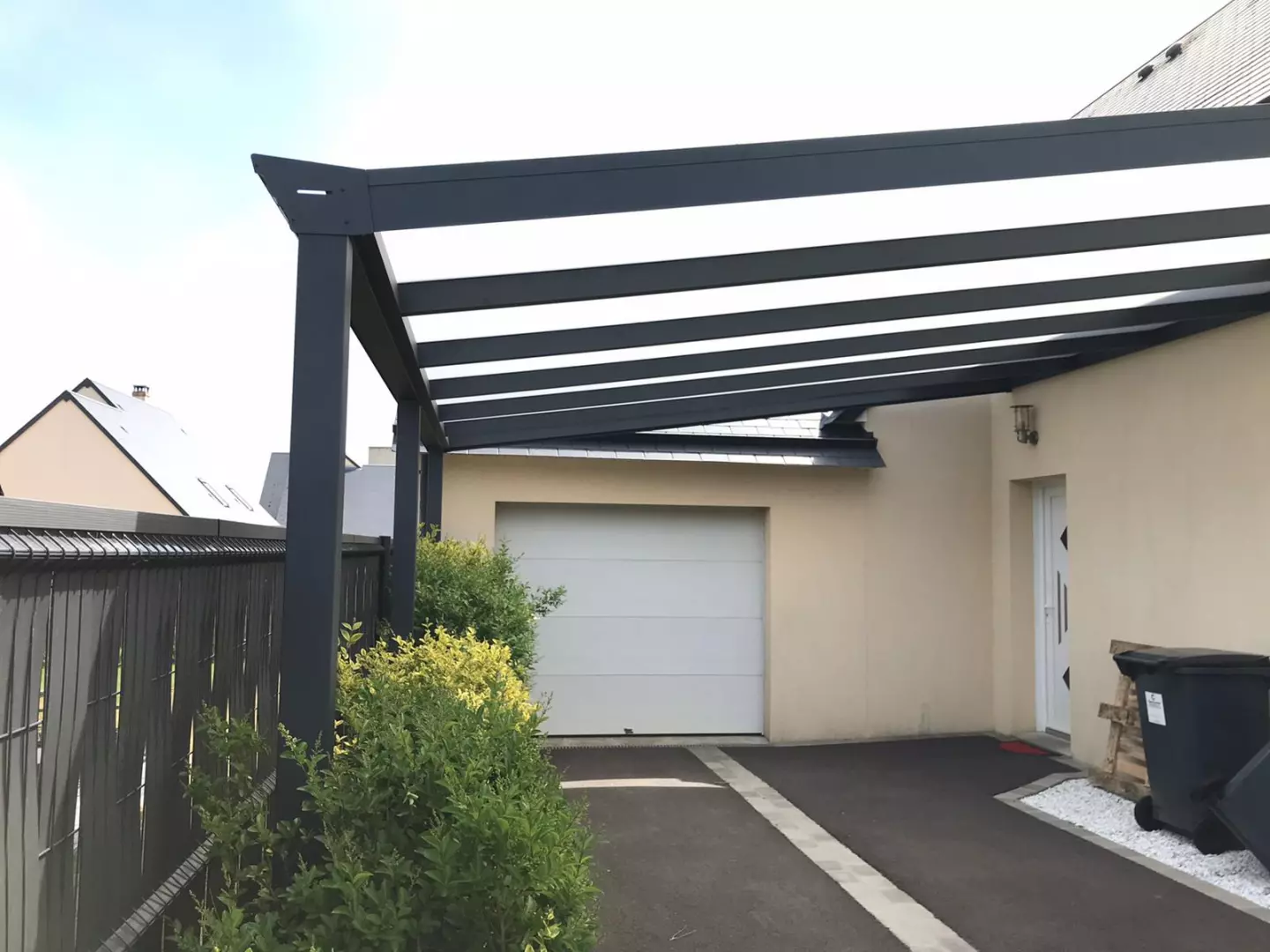 Carport alu anthracite toit polycarbonate translucide, adossé à façade beige