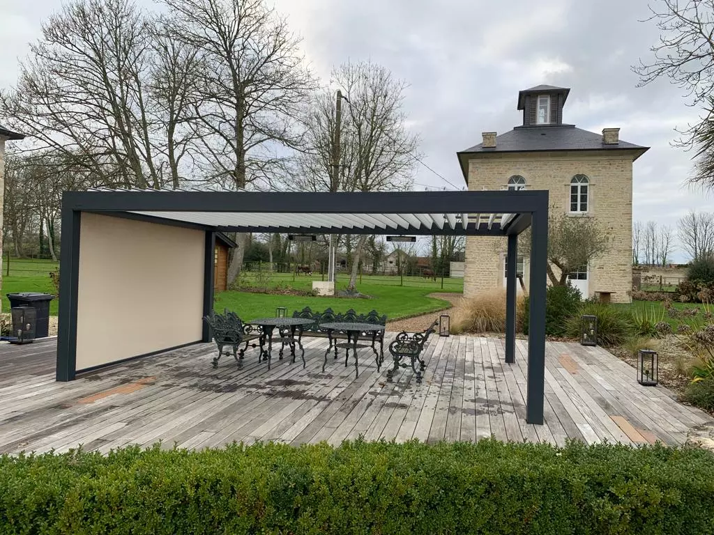 Pergola bioclimatique anthracite, lames blanches, store latéral beige, terrasse bois