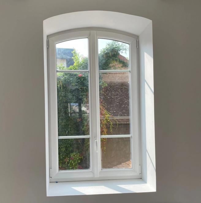 Fenetre PVC blanche cintrée a deux vantaux et petits bois, vue jardin depuis le salon