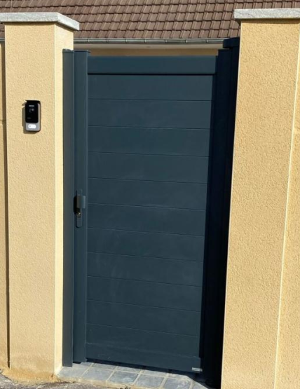 Portillon plein anthracite lames horizontales entre piliers beige toiture tuiles