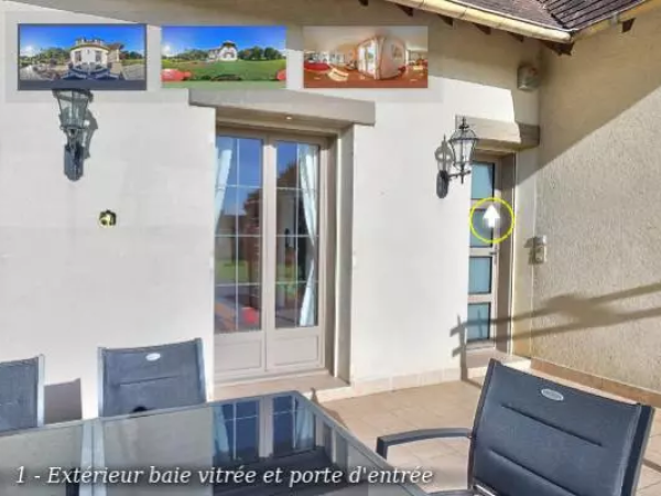 Baie vitrée et porte d'entrée grises sur façade crème, terrasse carrelée et salon de jardin