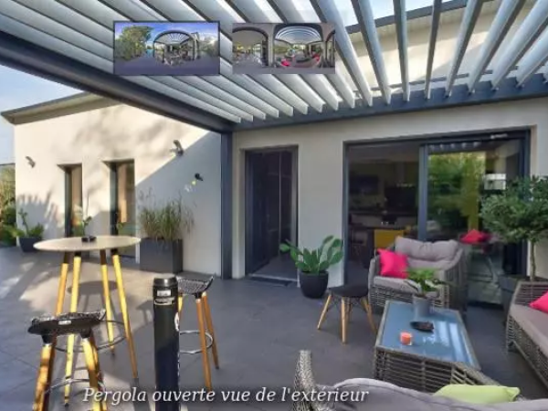 Pergola bioclimatique grise lames ouvertes, table haute ronde et salon gris à coussins roses