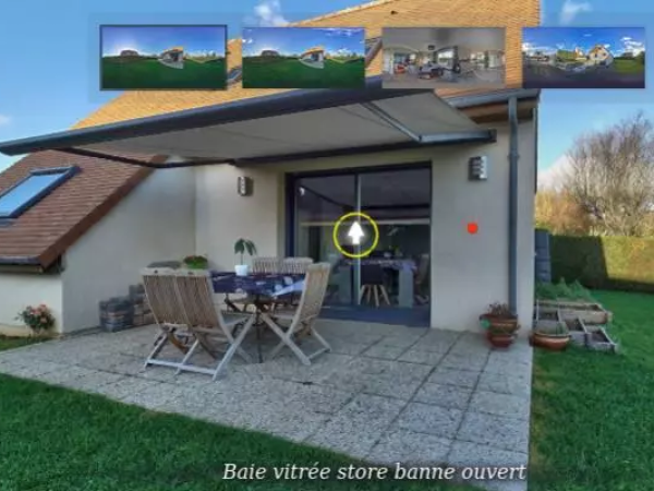 Store banne beige déployé sur terrasse pavée, table bois et baie vitrée sur façade claire