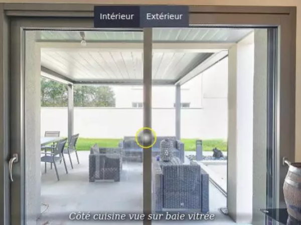 Baie coulissante anthracite vue cuisine, terrasse carrelée sous pergola et salon de jardin gris